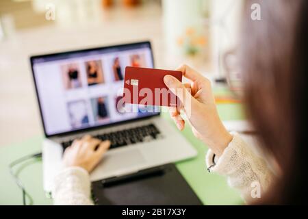 Gros plan d'une femme utilisant un ordinateur portable et une carte de crédit au bureau Banque D'Images