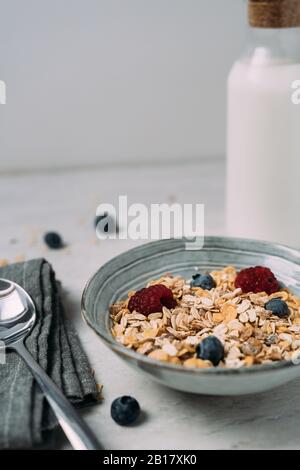 Bol de granola avec bleuets et framboises avec bouteille de yaourt en arrière-plan Banque D'Images
