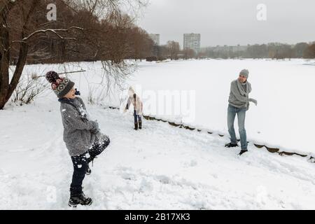 Père et de deux enfants ayant une snowball fight Banque D'Images