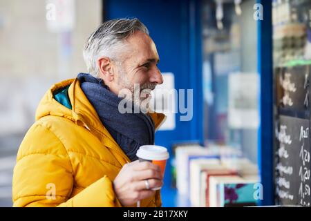 Homme mûr souriant dans un stand avec café à emporter Banque D'Images