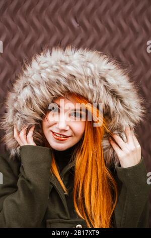 Portrait de jeune femme souriante à tête rouge portant une veste à capuche Banque D'Images