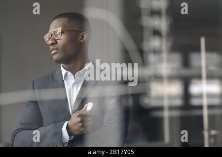 Portrait de jeune homme d'affaires derrière le diagramme sur la vitre au bureau Banque D'Images