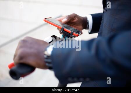 Vue de la récolte de l'homme avec scooter poussant à l'aide du smartphone Banque D'Images