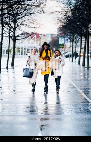 Les amies marchant dans la ville un jour de pluie Banque D'Images