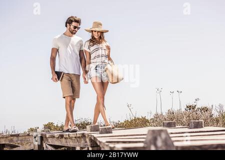 Un jeune couple marchant le long d'une promenade de la plage Banque D'Images