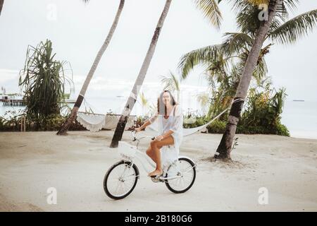 Femme à vélo sur la plage, île de Maguhdhuvaa, atoll de Gaafu Dhaalu, Maldives Banque D'Images