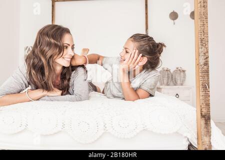 Mère et fille posée ensemble sur le lit se reposant Banque D'Images