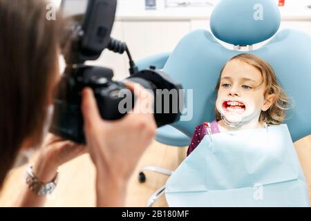 Dentiste prenant photo de fille recevant un traitement dentaire Banque D'Images