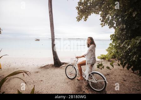 Femme avec vélo sur la plage, île Maguhdhuvaa, atoll Gaafu Dhaalu, Maldives Banque D'Images