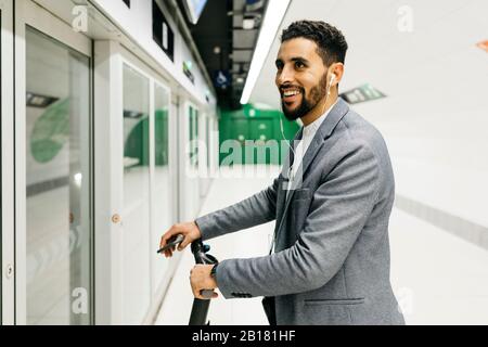 Jeune homme d'affaires avec scooter électrique dans la station de métro Banque D'Images