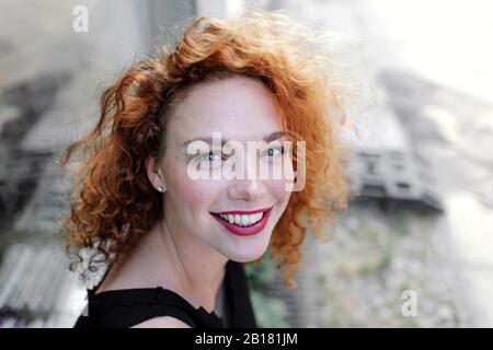 Portrait d'une femme souriante aux cheveux rouges regardant l'appareil photo Banque D'Images