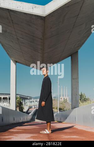 Jeune homme portant un caftan noir debout sur un pont de pied Banque D'Images