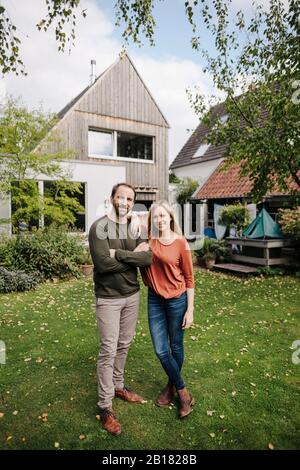 Fiers propriétaires de maison debout dans leur jardin Banque D'Images