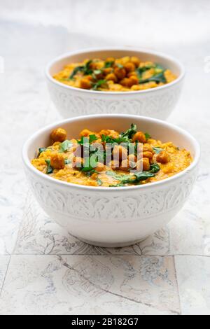 Curry de lentilles végétaliennes avec lentilles rouges, patates douces, épinards, curcuma rôti, pois chiches, jus de citron vert et coriandre Banque D'Images