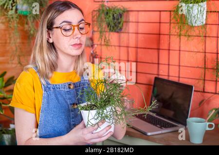 Femme prenant soin d'une usine de Rhipsalis sur sa terrasse Banque D'Images