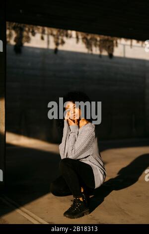 Portrait d'une belle jeune femme qui s'accroupe à la lumière du soleil Banque D'Images