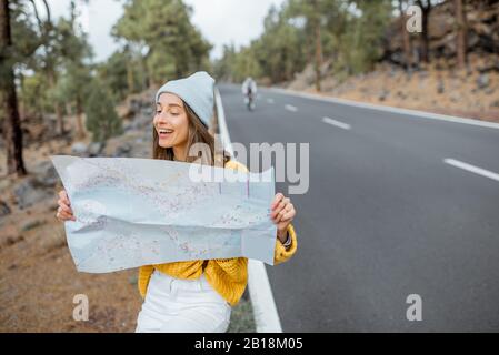 Portrait d'une jeune femme élégante avec carte papier sur le côté de la route, se déplaçant dans la forêt Banque D'Images