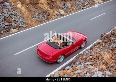Vue sur le paysage sur la magnifique route droite sur la vallée volcanique avec une femme conduisant un cabriolet rouge, vue d'en haut. En voiture sur l'île de Tenerife, Espagne Banque D'Images