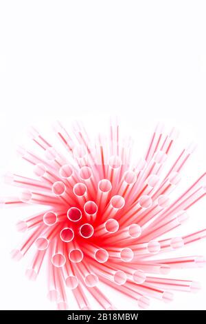 Pailles en plastique avec bandes rouges et blanches dans un groupe isolé sur un fond blanc. Concept de déchets plastiques Banque D'Images