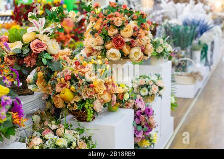 Bouquet de roses blanches jaunes artificielles avec feuilles et fruits, décoration intérieure une rangée de bouquets dans un fleuriste, décoration tissu de fleurs artificielles Banque D'Images