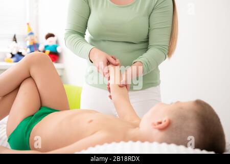 Kids concept massage arrière-plan. Jeune femme massothérapeute donnant un garçon de 6 ans massage des bras. La thérapie physique. Banque D'Images
