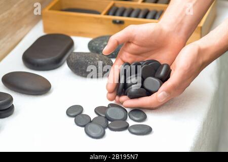 Pierres de massage noires dans les palmiers mâles sur la table, gros plan. Banque D'Images