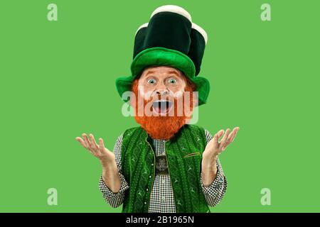 Étonnés, surpris. Lepreun excité en costume vert avec barbe rouge sur fond vert. Portrait drôle de l'homme prêt à la fête. Saint Patrick jour, émotions humaines, célébration, vacances traditionnelles. Banque D'Images