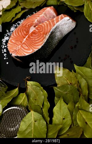 Coupez le poisson rouge fraîchement salé en tranches avec du sel de feuille de laurier grossier et des pois de poivre noir dans un bol. Banque D'Images