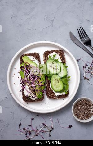 sandwich végétalien avec avocat, concombre et fromage à la crème sur fond gris. vue du dessus Banque D'Images