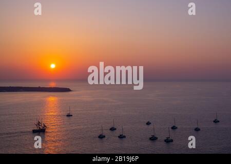 Les yachts de croisière au coucher du soleil ont navigué et ancré dans un endroit clair, laissant les touristes à bord profiter du coucher du soleil. Banque D'Images