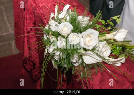 Bouquet de fleurs de calla et de roses blanches sur un tissu rouge. Gansets. Roses. Zantedeschia aethiopica. Banque D'Images