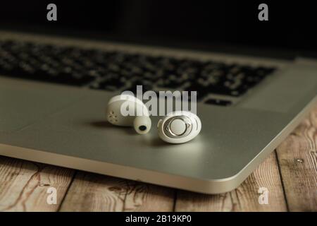 Casque sans fil blanc et ordinateur portable sur fond en bois gros plan, sans boîtier Banque D'Images