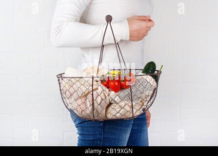 La femme garde le dos avec des légumes frais et des fuits dans des sacs textiles Banque D'Images