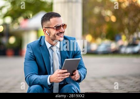 Un jeune homme d'affaires attrayant utilisant une tablette numérique.Portrait de beau homme d'affaires en plein air dans la ville.Jeune homme d'affaires de vérifier l'e-mail Banque D'Images