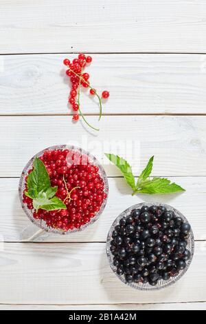 Baies de cassis rouge, sur fond de bois blanc. Photo verticale. Banque D'Images