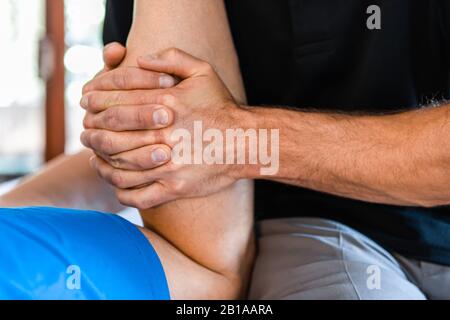 Vue rapprochée des mains masseuses massant les jambes du sportif masculin. Massothérapeute travaillant avec la pression sur les jambes. Massage thérapeutique du corps Banque D'Images