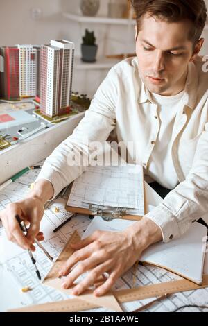 jeune concepteur professionnel utilisant une règle, une paire de compas, la préparation d'un nouveau projet, la mesure de la gravure. gros plan photo. photo verticale Banque D'Images
