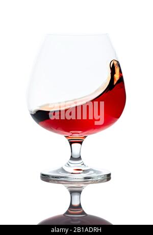 Projection de cognac en verre, isolée sur fond blanc. Banque D'Images