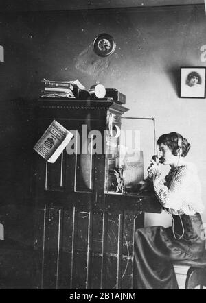 Pupitre de commande téléphonique (unité unique) avec opérateur de femme, port d'écouteurs. Vers 1917, Minneapolis, Minnesota annuaire téléphonique suspendu du côté du standard. Pour voir mes autres images anciennes, recherchez: Prestor vintage woman Banque D'Images