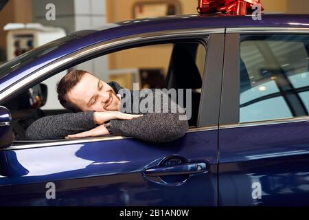 client barbu gai allongé sur la voiture, prêtant qu'il embrassant le véhicule, chaud tendre sensation, tendresse, meilleur ami, concept d'amitié Banque D'Images