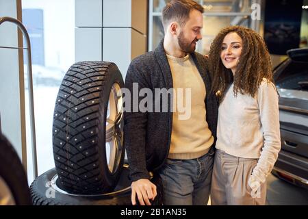 jeune homme et sa femme achetant des pneus pour voiture, shopping, homme donnant des conseils à sa femme ce qui pneus à acheter. Banque D'Images