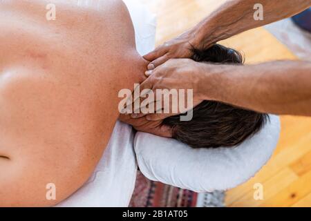 Un masseur inreconnaissable donnant un massage de la tête et du cou à un patient masculin fort. Ostéopathie et réadaptation des blessures sportives Banque D'Images