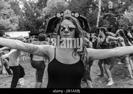 Une vue monochrome créative d'une femme tatouée en bonne santé portant un gilet noir aux bras ouverts lors d'un festival multiculturel célébrant la terre et la spiritualité