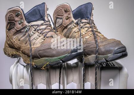 Chaussures de marche/randonnée humides et boueuses placées sur un chauffe-huile portable, pour sécher. Banque D'Images