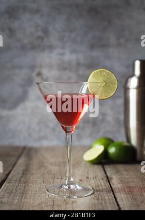 Gros plan sur une table en bois, on y trouve une boisson cosmopolite au martini et un shaker. Banque D'Images