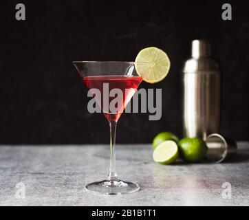 Boisson cosmopolite martini, shaker et limes sur un comptoir gris. Banque D'Images