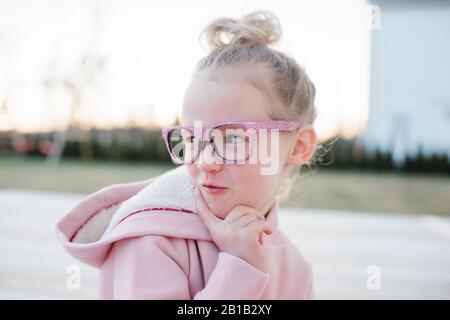 portrait d'une jeune fille tirant des visages drôles avec des lunettes roses Banque D'Images