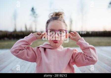 portrait d'une jeune fille tirant des visages stupides avec des lunettes roses étincelantes Banque D'Images