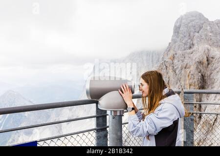 les jeunes femmes regarde la vue sur la montagne depuis des jumelles depuis l'observation Banque D'Images