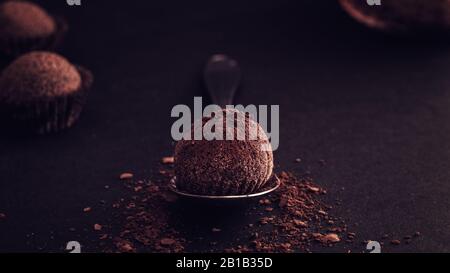 Gros plan sur les truffes belges avec poudre de cacao sur fond noir de table de bois Banque D'Images